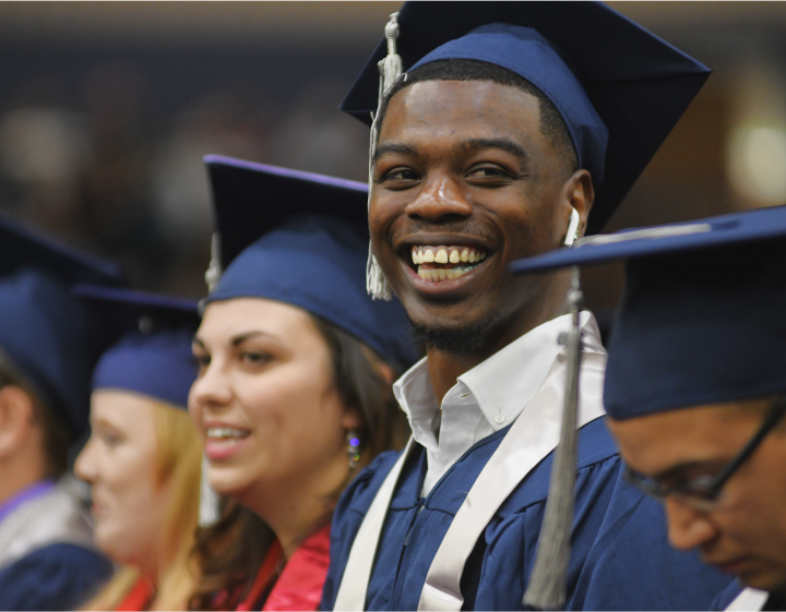 Students in graduation garb, smiling