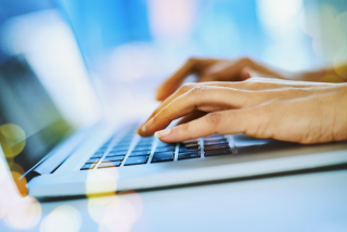 Hands typing on a laptop computer.