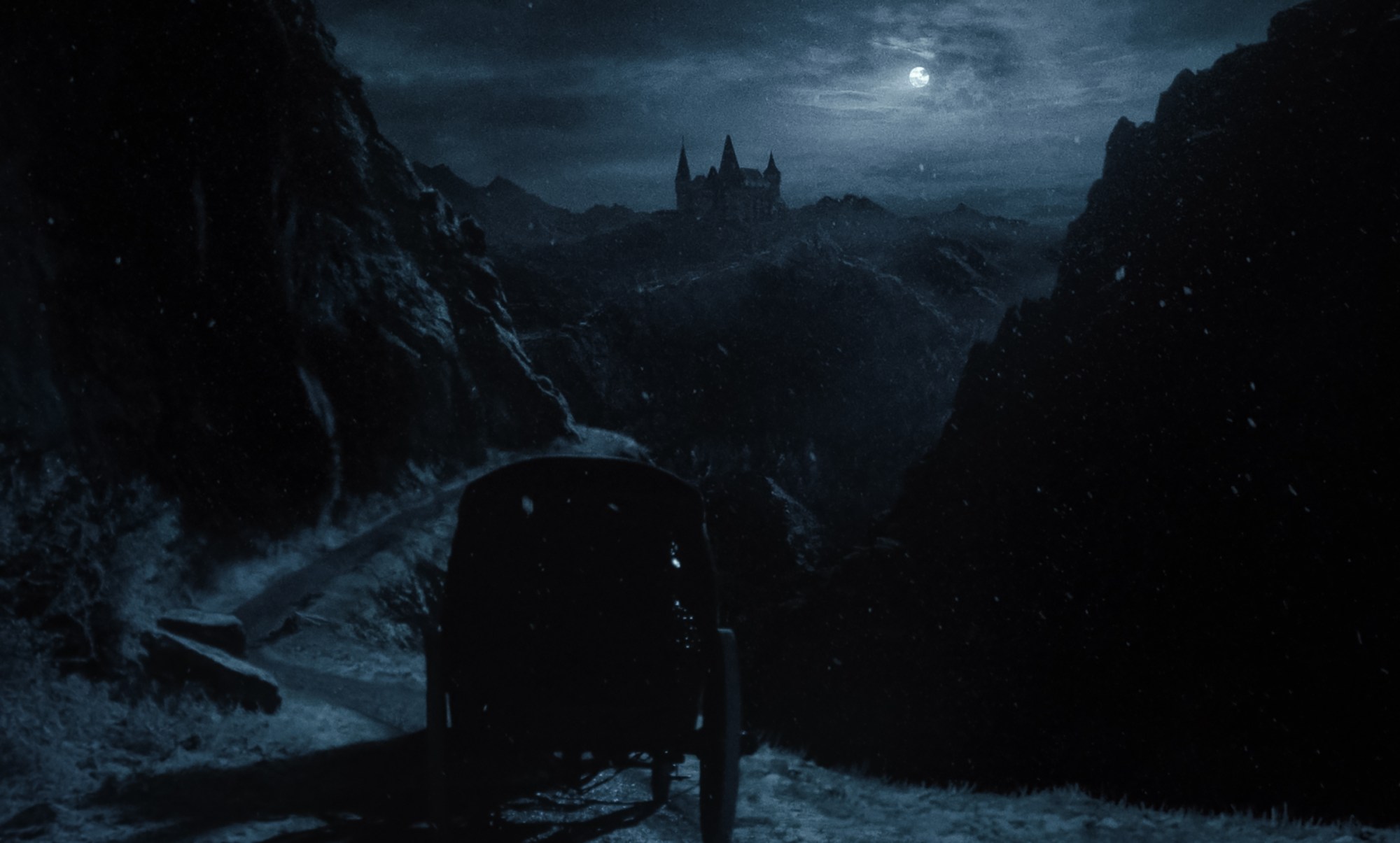 A film still of a castle and a carriage in Robert Eggers' Nosferatu.