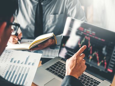 Midsection View of Businessmen Analyzing Charts on Laptop in Office