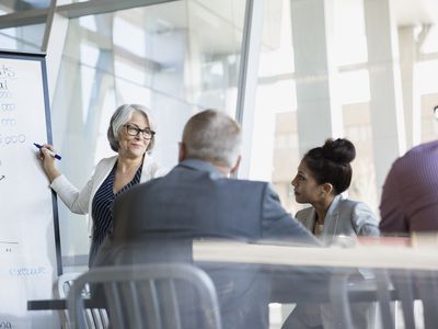 Businesswoman at whiteboard leading meeting in conference room