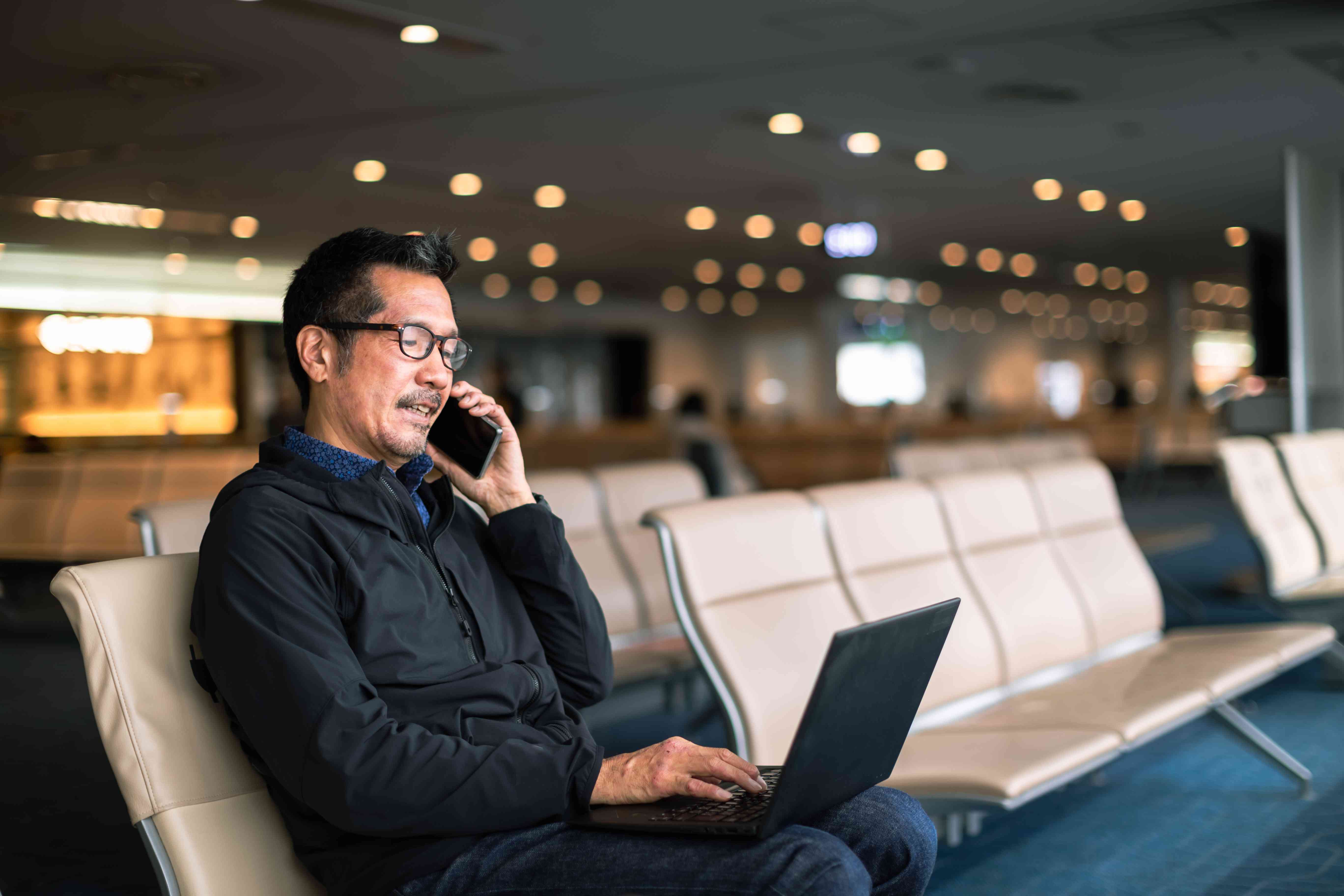 A man talks on the phone in an airport.