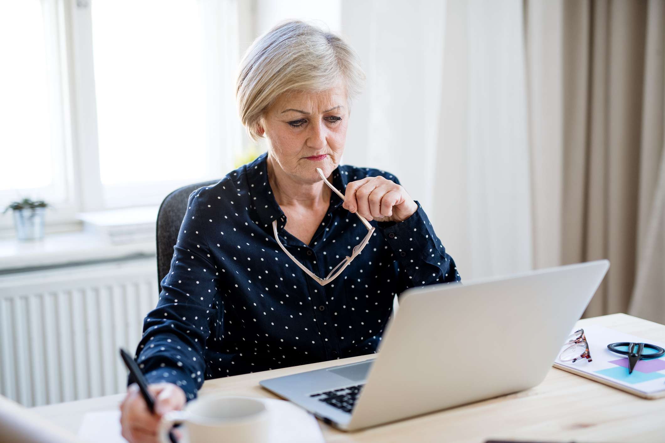 A woman with laptop working in home office with her laptop.