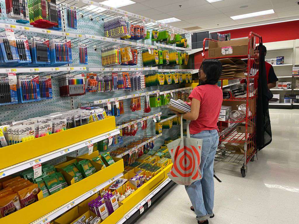 Customer shopping for school supplies with employee restocking shelves, Target store, Queens, New York.