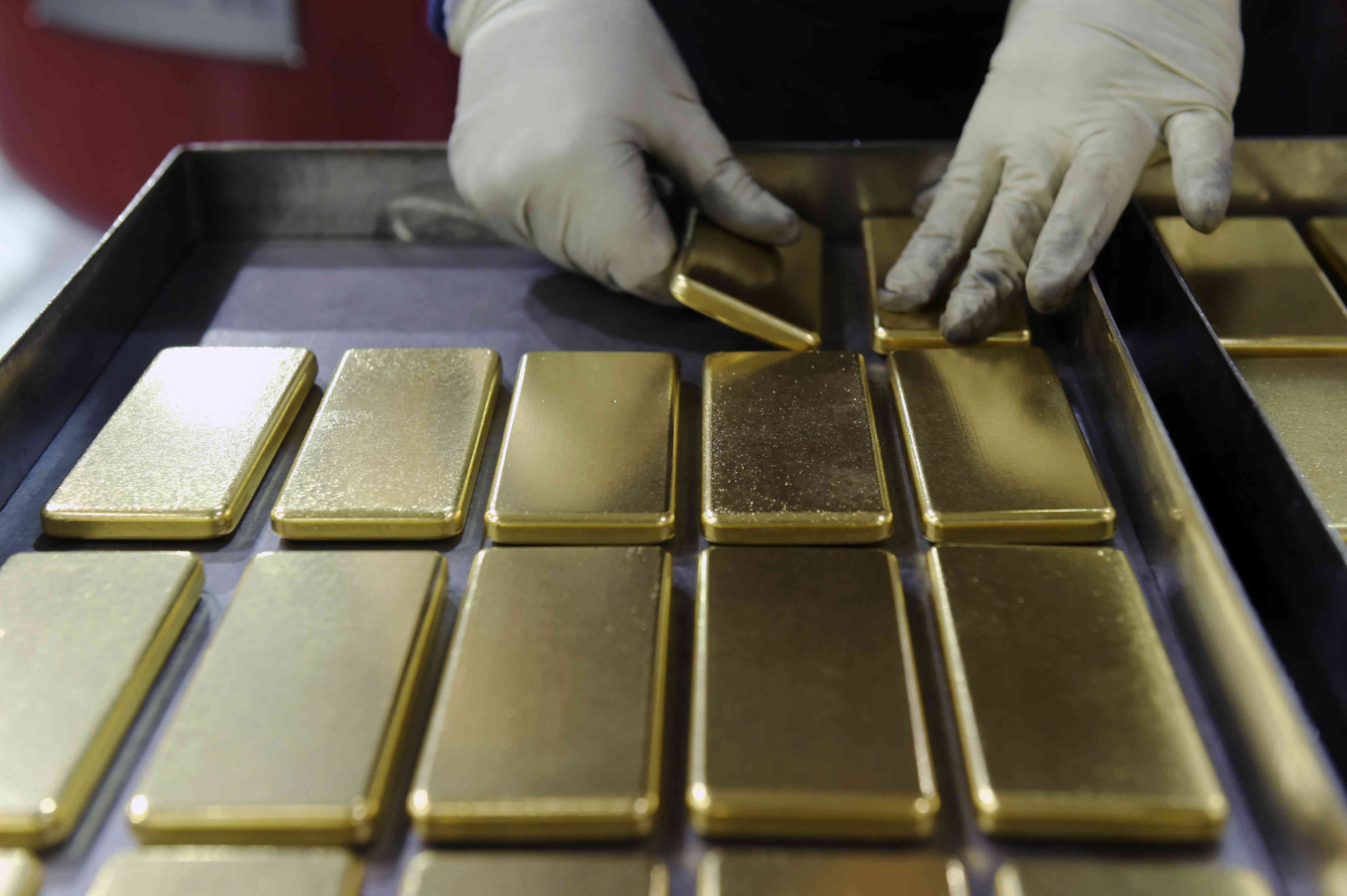 An employee places one kilogram gold bars into a transport case in prepration for transfer to a buyer.