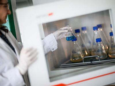 A scientist holds a beaker containing liquid in a lab.