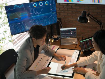 Two business people and women discussing over digital tablet at desk in office