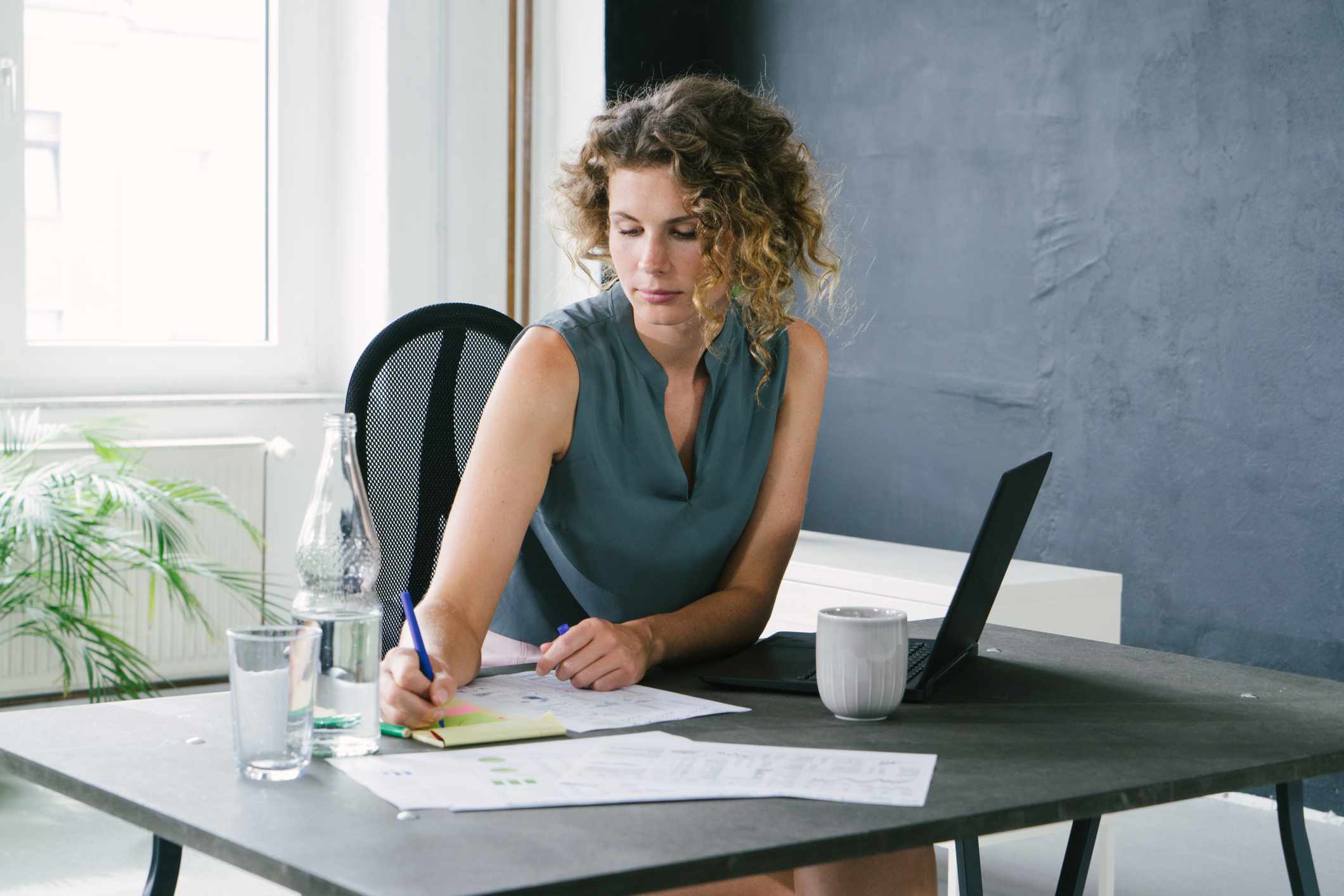 Young businesswoman sitting at her office desk, signing documents.