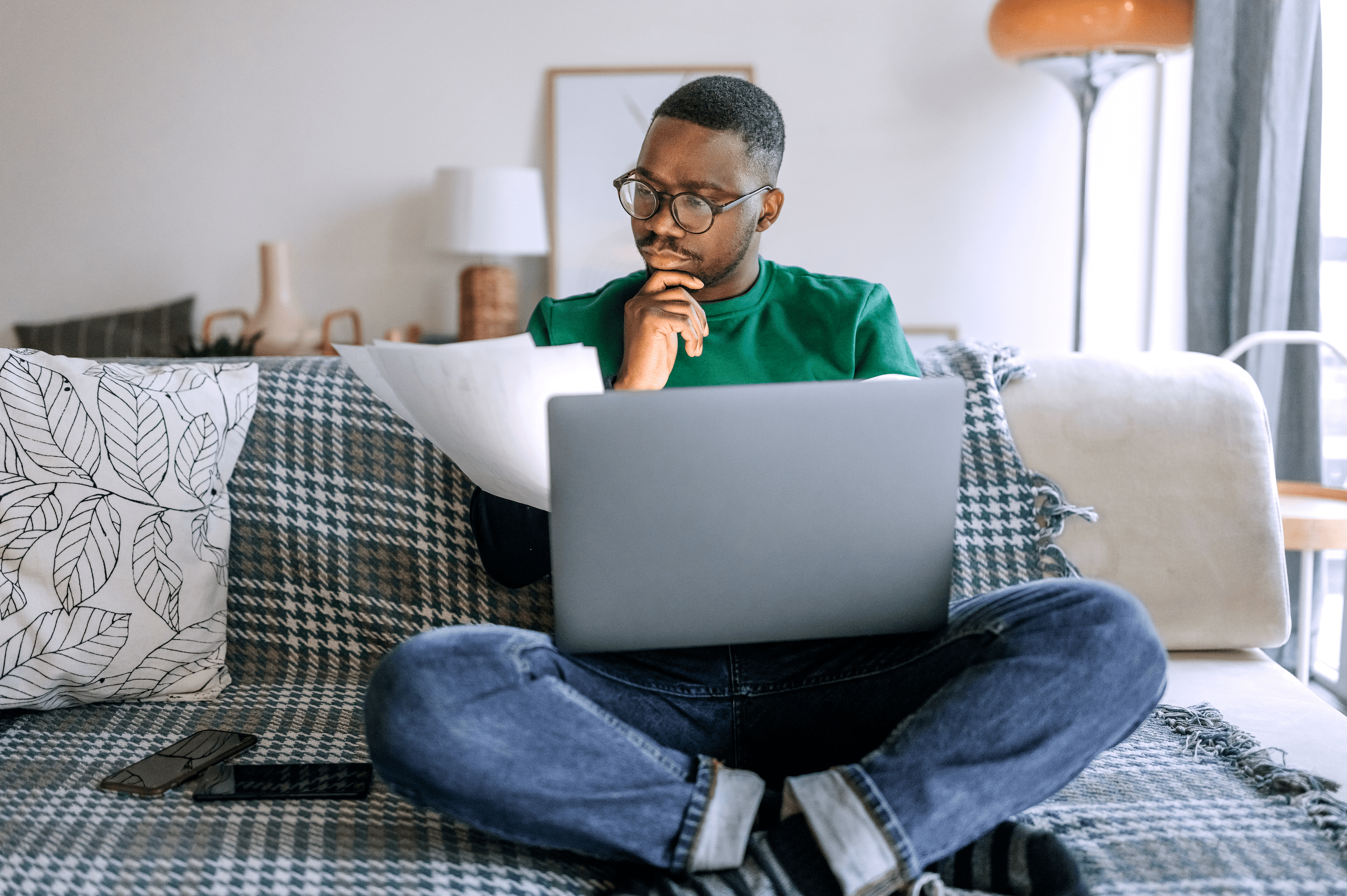 Young Black man pondering a financial statement while sitting at home in front of a laptop