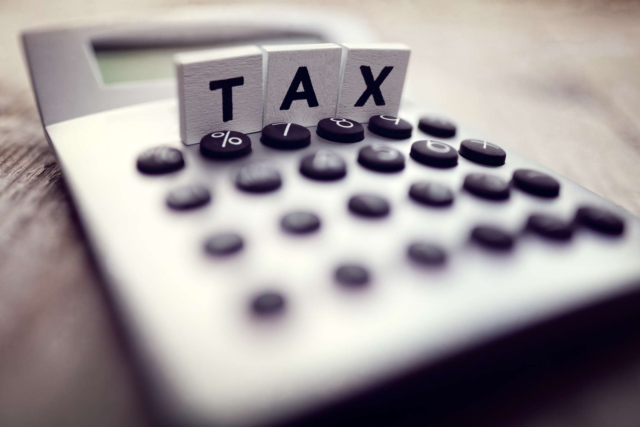 A calculator with wood blocks that say tax