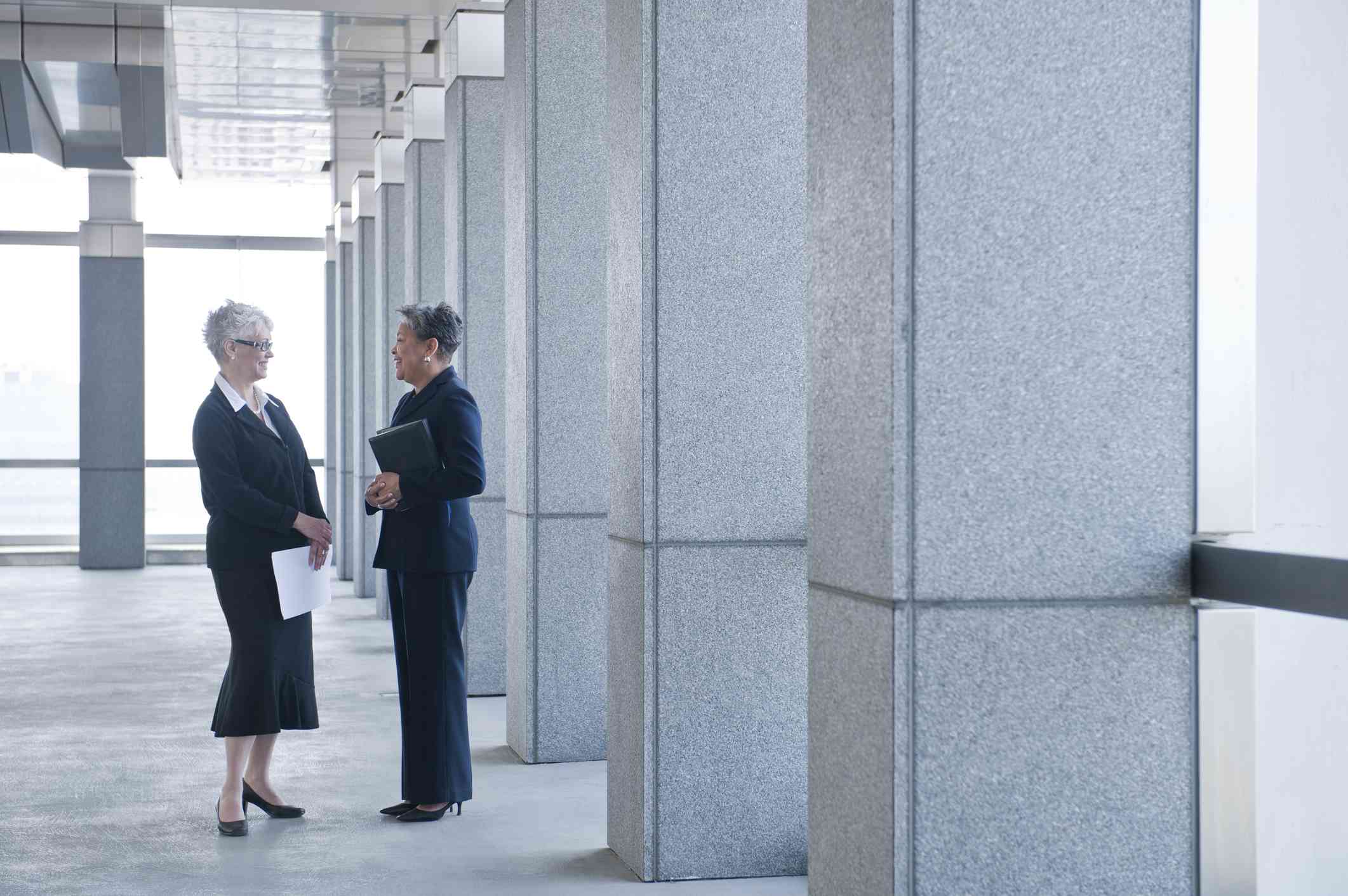 Two women in suits are talking.