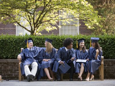 Five graduates sitting on a bench