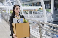 Woman carrying a box of work supplies away from an office building