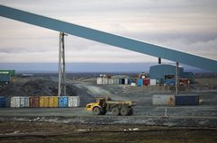 A truck at a mining site passes by a large conveyor machine transporting rock containing gold to a processing plant. 