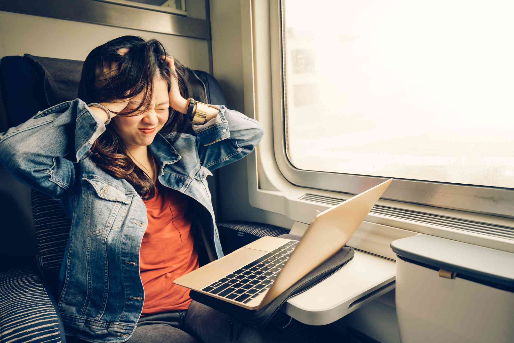 Asian college girl frustrated with laptop on the train.