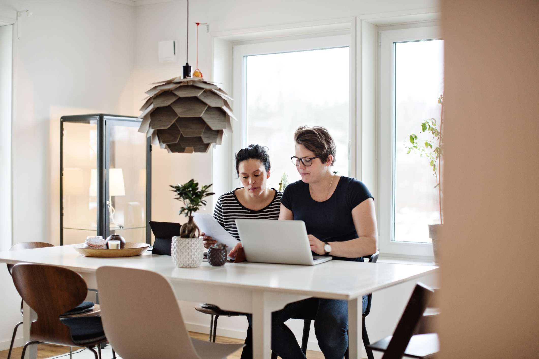 A couple discussing financial bills over laptop while sitting at table.