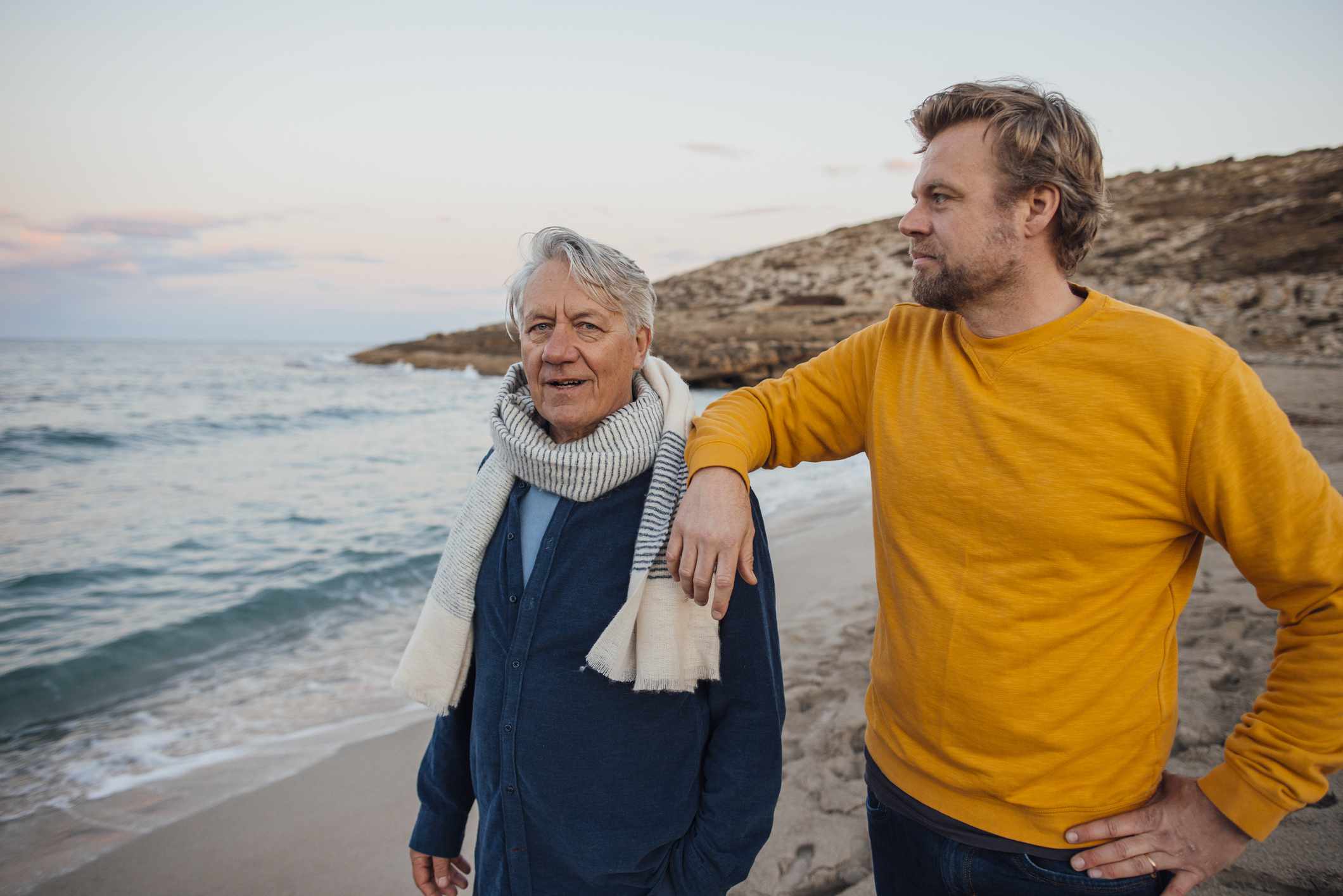 Two men, one older and one younger, on a beach. 