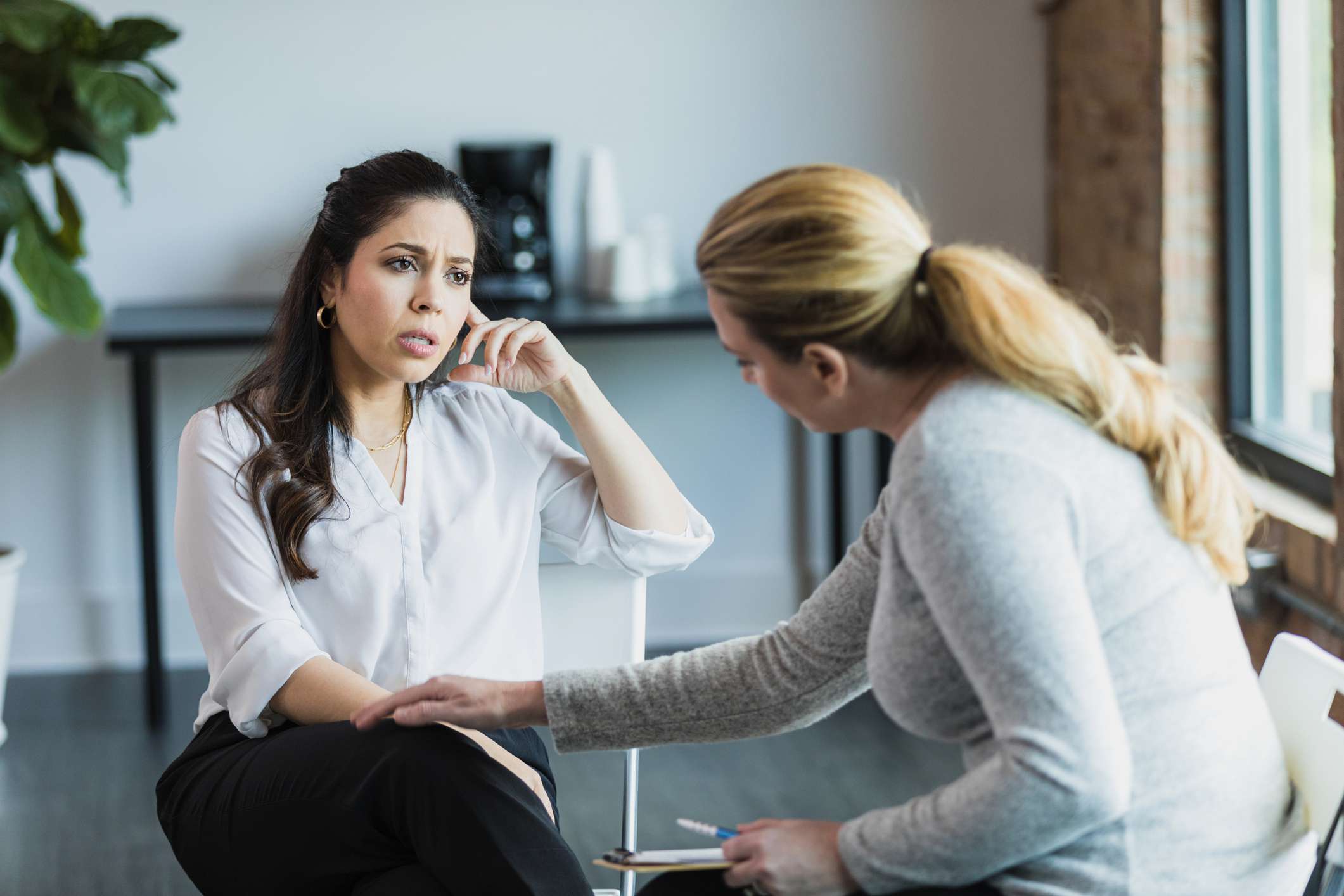 Mid-adult woman is sad and female therapist comforts