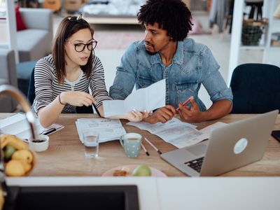 Two young people look through paperwork at a desk.