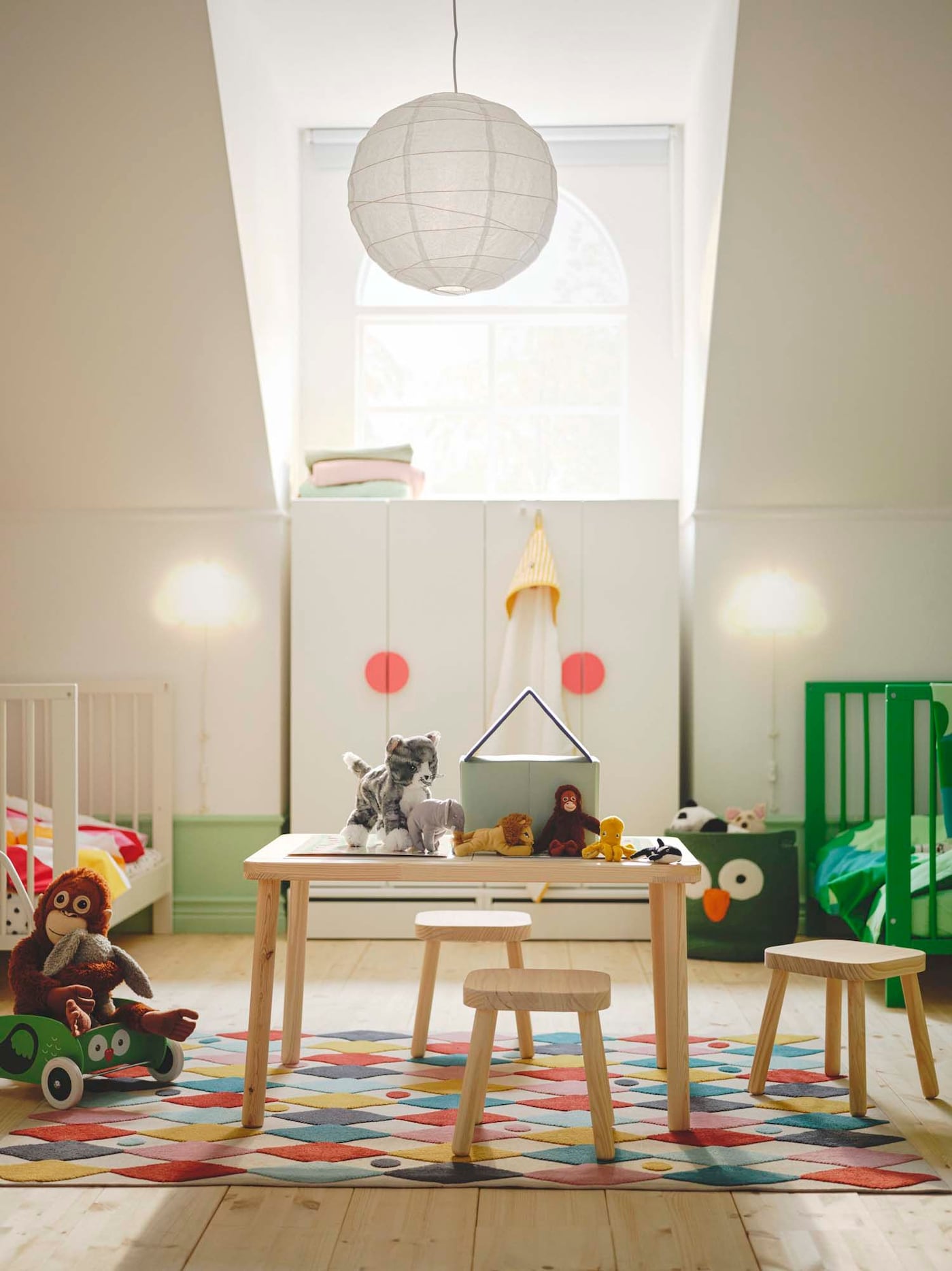 A toddler bedroom with a small table and chairs in the centre with a lamp hanging above.