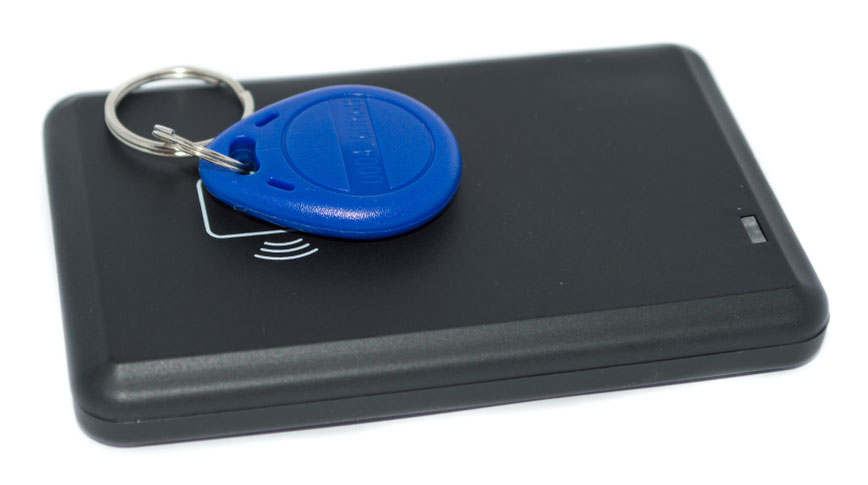 An RFID key fob is placed on an RFID reader.