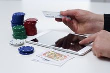 Credit card in hand with casino paraphenalia and a tablet