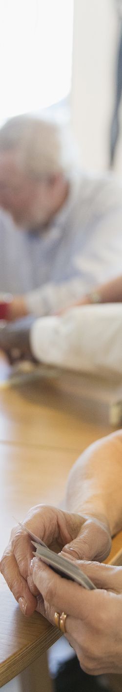 senior woman playing cards with friend at table in community center