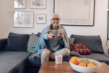 A woman sitting on a couch, holding a remote control