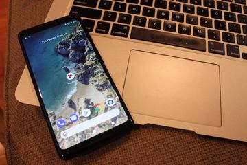 A Google Pixel 2 phone resting on the wrist wrest of a MacBook Air.