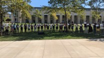 Carnegie Mellon students, professors, and alumni line up on a quadrangle holding signs labeled "1" through "29"