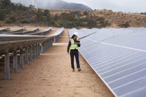 Field engineer inspects solar panels on a wind farm using remote assist with a Surface tablet.