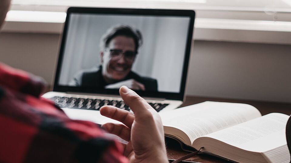 Person vor einem Laptop-Bildschirm als Teilnehmer einer Online-Veranstaltung