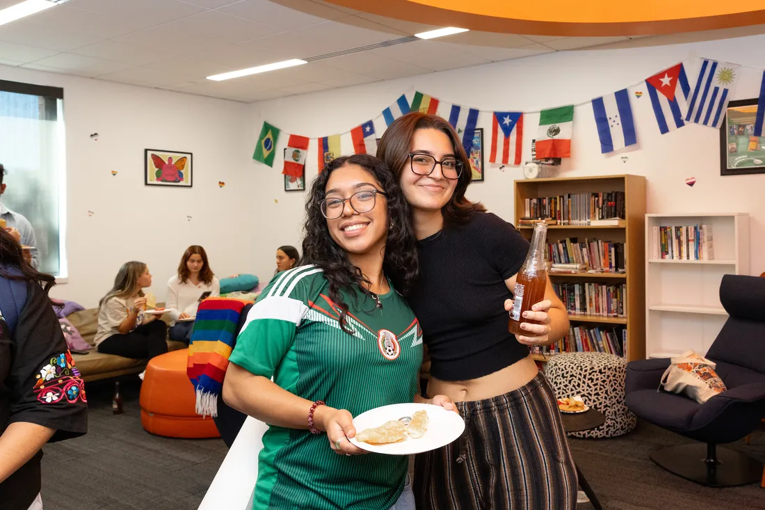 Two students standing and smiling together.