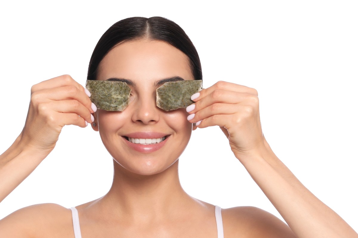 A woman holding tea bags over her eyes. 