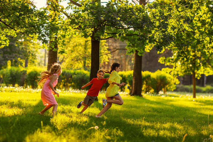 Three kids run in a field.