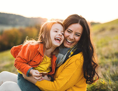 IMAGE: mother hugging young daughter on a hillside