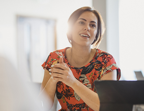 IMAGE: Woman sitting behind a computer talking and smiling