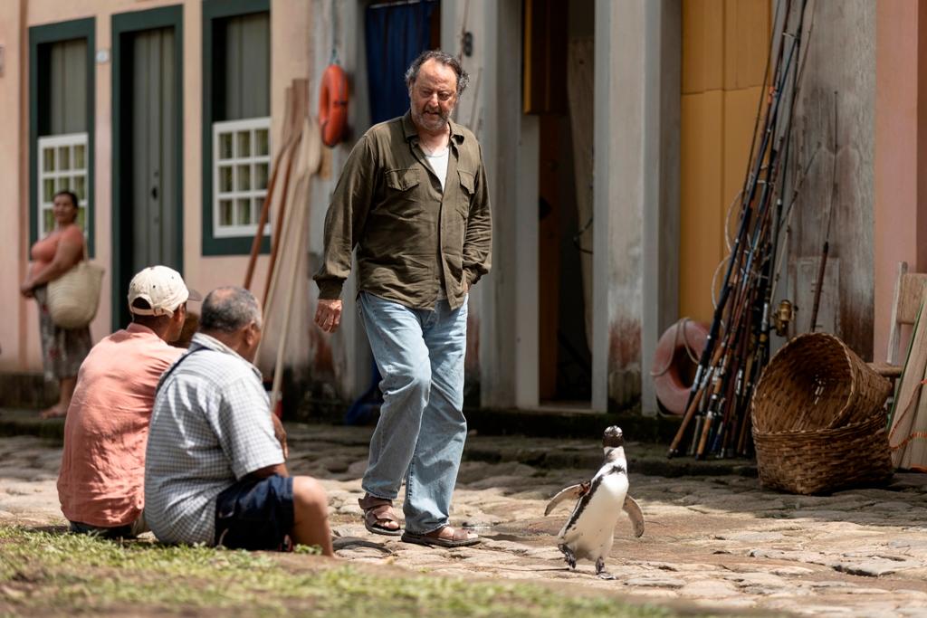 Joao (Jean Reno) and DinDim take walks through town, in "My Penguin Friend." (Roadside Attractions)