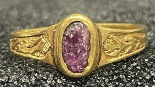 The ring is carved with foliate designs around a central stone, which may be amethyst