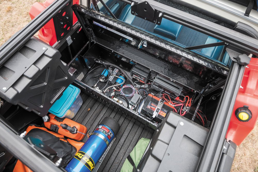 contents of bed of 1978 Jeep J20 which shows Powertank, electronics, storage containers.