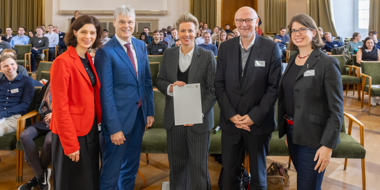 Ministerin Ina Brandes (Mitte) überreichte Dr. Julia Quante, Prorektor Prof. Dr. Michael Quante (v.l.), Prof. Dr. Martin Winter und Dr. Kerstin Neuhaus den Förderbescheid für die internationale Forschungsschule „BACCARA“ an der Universität Münster.<address