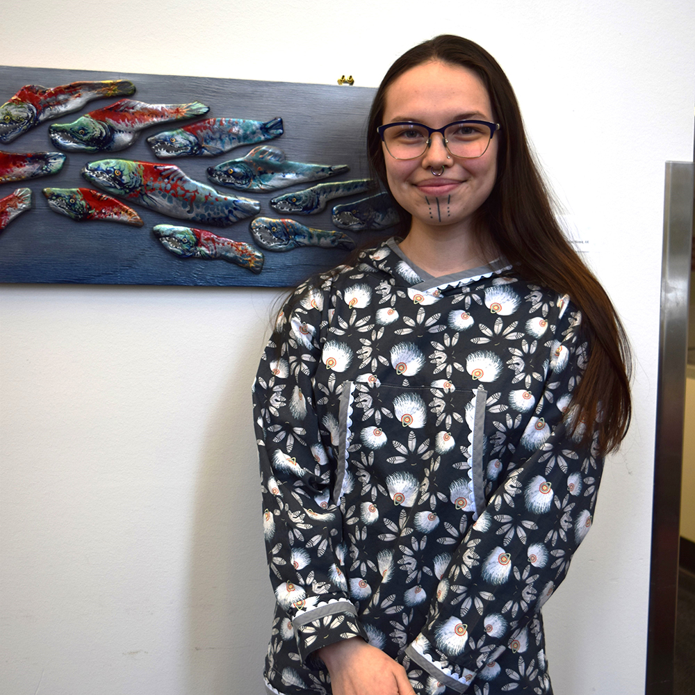 Robin Masterman standing in front of artwork of salmon