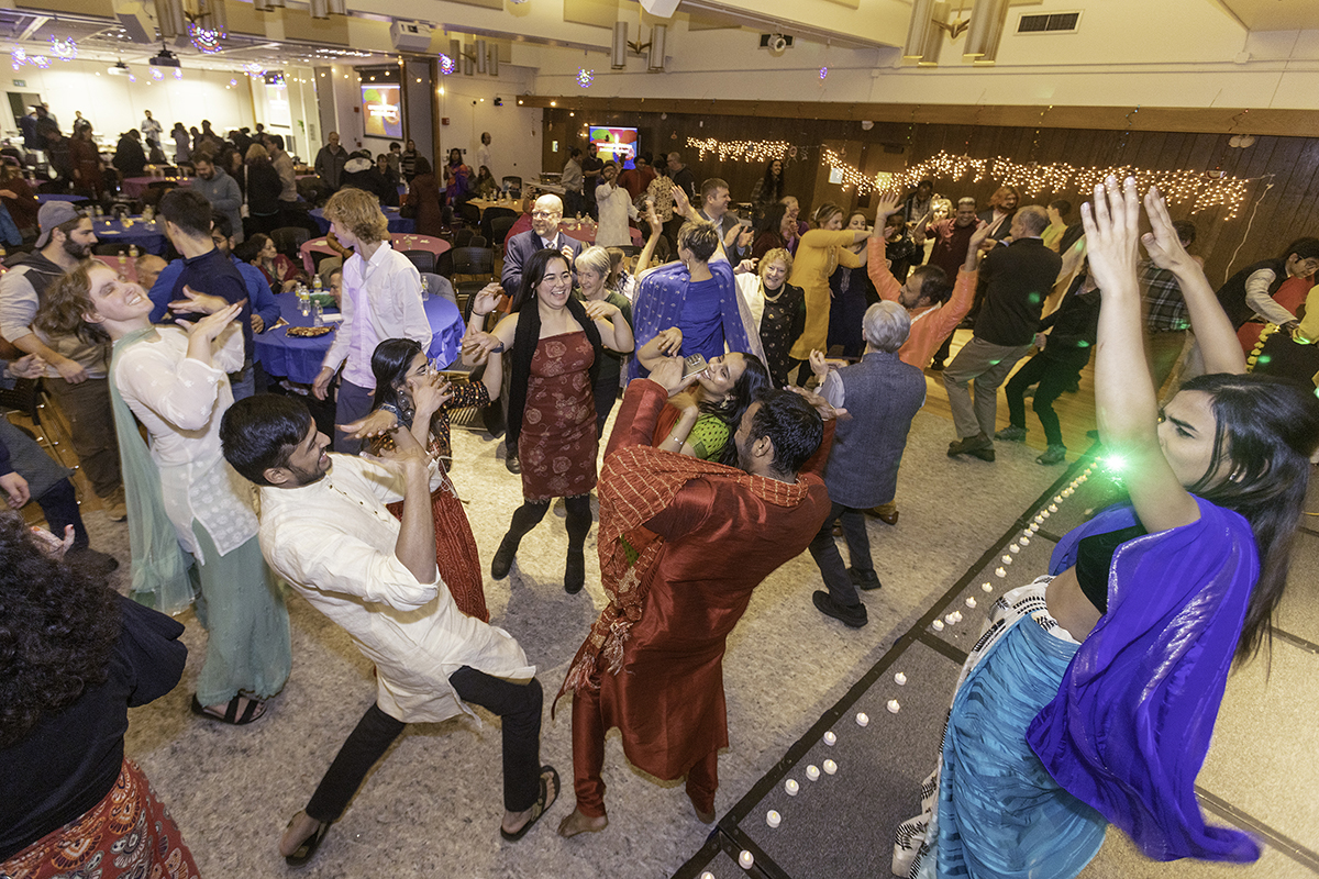 a crowd of colorfully dressed people dance together in a ballroom