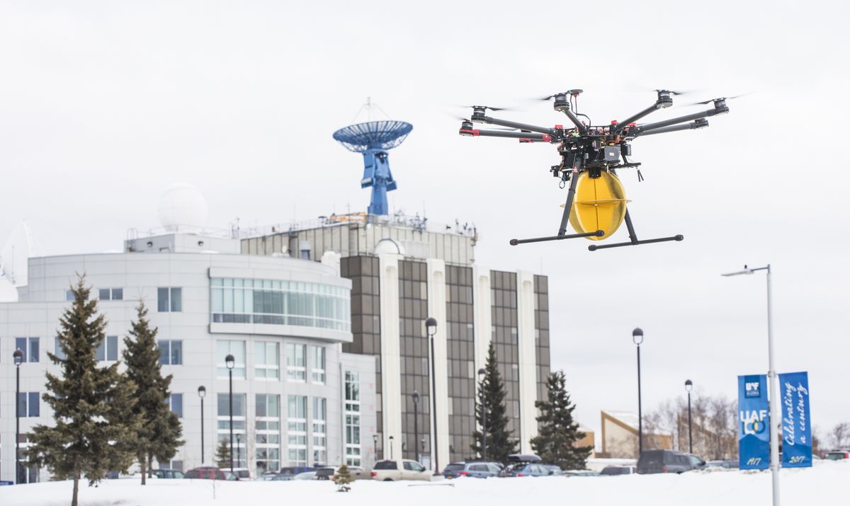 A drone hovers above the UAF campus in winter.