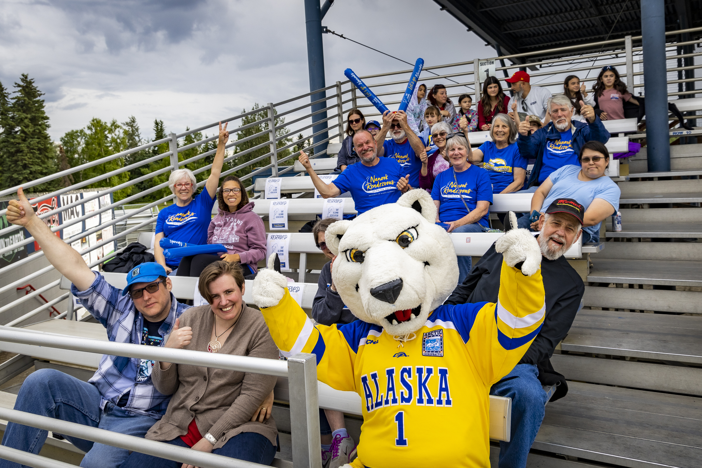 People in the stands at a game cheer with a polar bear mascot in costume.