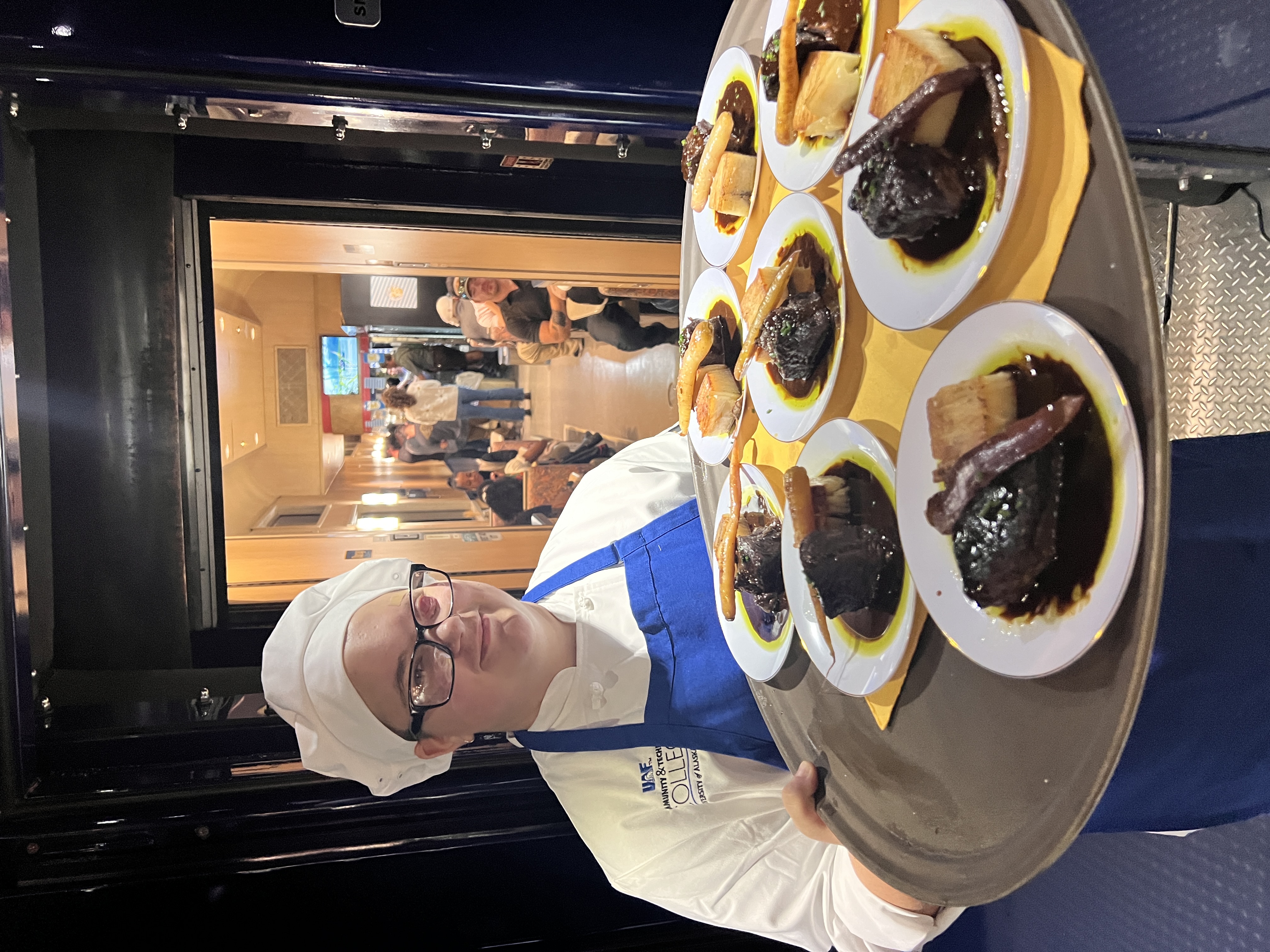 Culinary Arts and Hospitality student Alex Adams serves a course to guests on the 2024 HooDoo Choo-Choo.