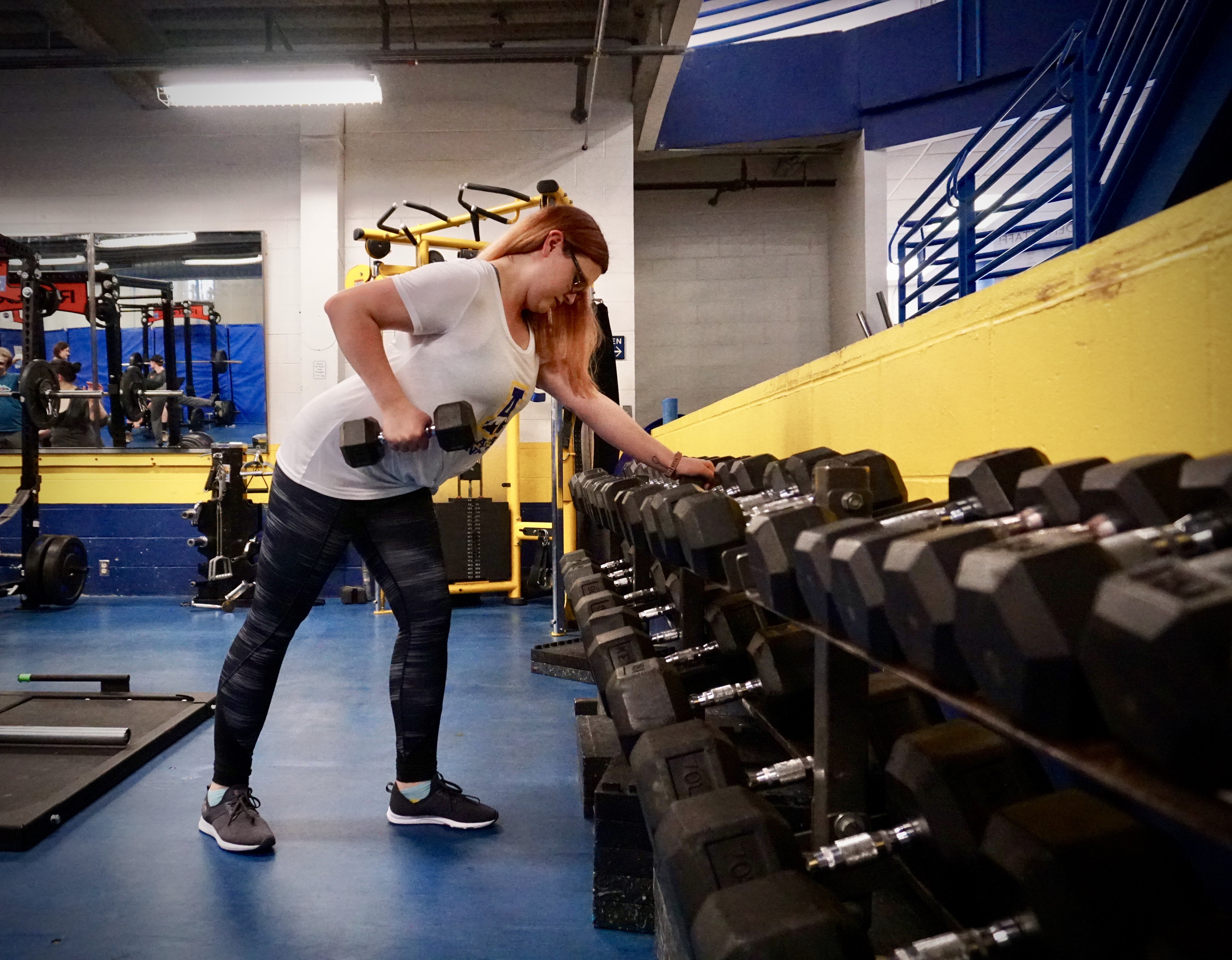 A person lifts a dumbell in a weight room