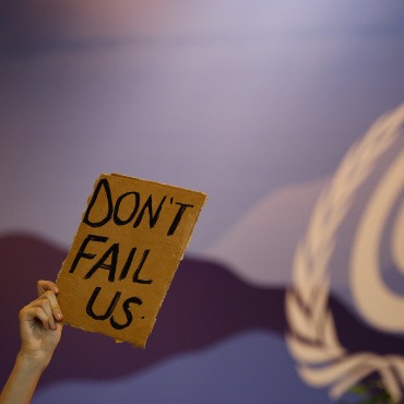 Hand hold cardboard up with "don't fail us" on it.