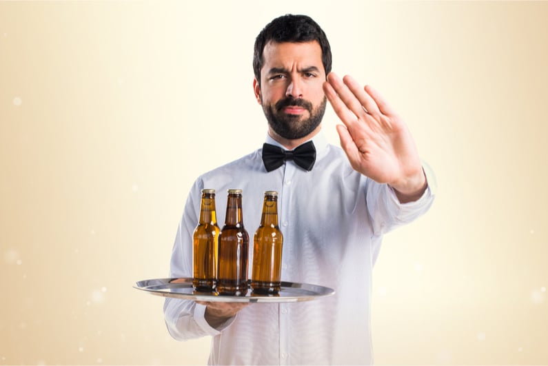 Waiter with beer bottles on the tray making stop sign
