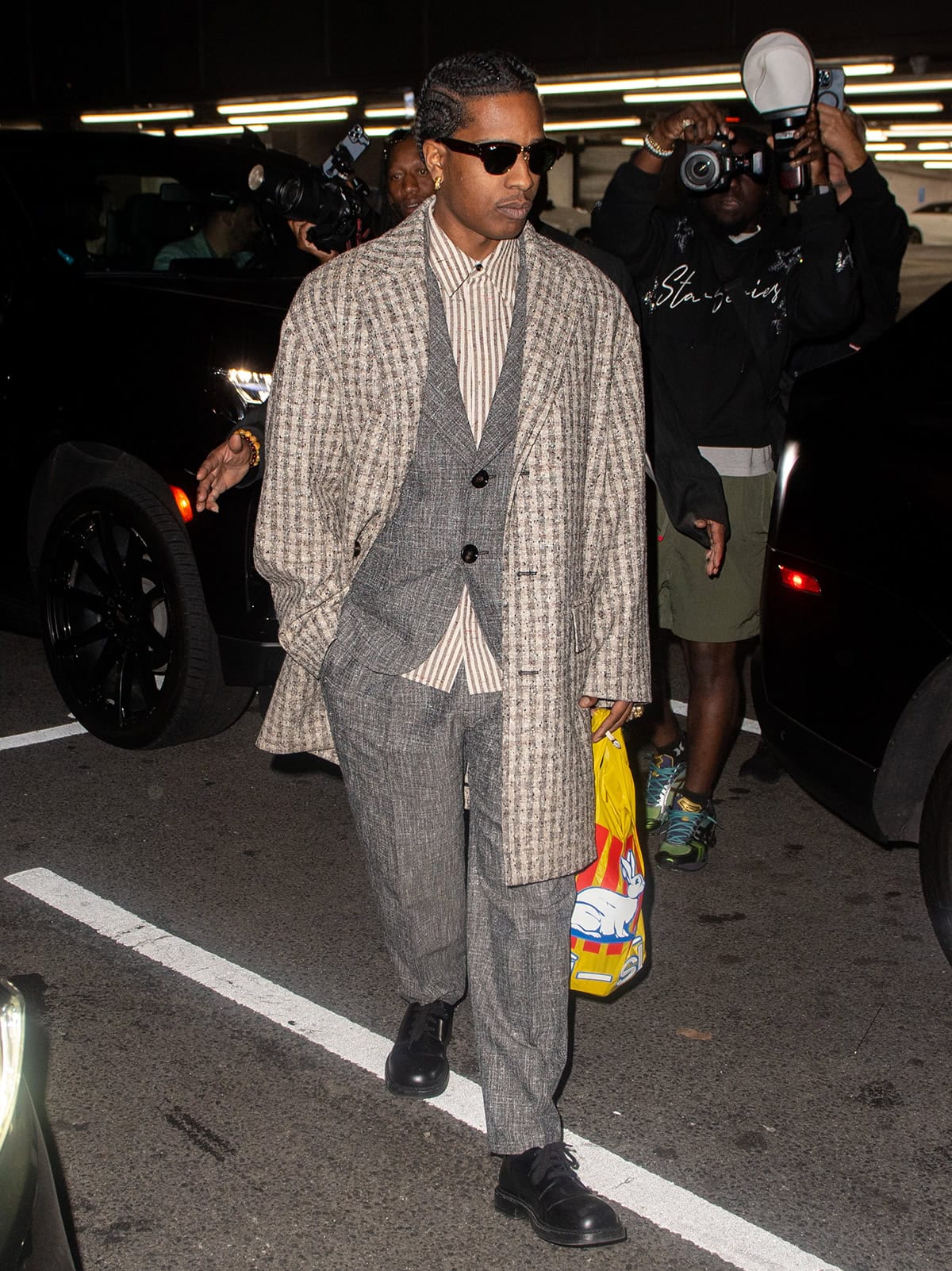 ASAP Rocky celebrates his 36th birthday in a Bottega Veneta gray suit with a striped shirt, a plaid tweed coat, and black derby shoes